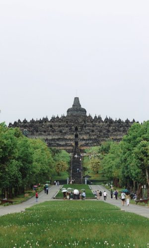 People visiting the iconic Borobudur Temple in Central Java, Indonesia, on a cloudy day.